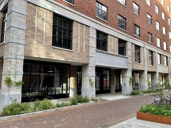 Entree van het moderne appartementencomplex "The Clark" aan de Karl Weisbardstraat met bakstenen gevel en grote ramen.